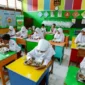 Inovasi Skema MBG Ramadan: Menu Bawa Pulang untuk Anak Sekolah

Pemerintah meluncurkan pendekatan baru dalam program Makan Bergizi Gratis (MBG) bagi anak sekolah selama bulan Ramadan. Dalam skema yang diperbarui, makanan tidak hanya dikonsumsi di sekolah, tetapi juga disediakan untuk dibawa pulang, sehingga dapat dinikmati saat berbuka puasa.

Kepala Badan Gizi Nasional, Dadan Hindayana, menjelaskan bahwa mekanisme baru ini sudah diberlakukan sejak 6 Maret 2025. “Meski konsepnya berubah, besaran biaya MBG selama Ramadan tetap sama seperti hari biasa. Semua anak sekolah akan menerima makanan yang bisa dibawa pulang secara serempak,” ungkapnya.

Detail Skema dan Menu
Menurut Dadan, menu MBG dirancang agar tahan lama, sehingga aman untuk disimpan hingga waktu berbuka puasa. Menu tersebut meliputi telur rebus, susu, kurma, kue kering fortifikasi, dan buah-buahan. “Kami juga menambahkan variasi seperti bubur kacang hijau atau kolak secara berkala, untuk memastikan komposisi gizinya tetap seimbang antara protein, karbohidrat, dan serat,” tambahnya.

Sebelumnya, pelaksanaan MBG dilakukan pada pagi hari sekitar pukul 09.00 WIB, yang membuat jarak waktu cukup jauh hingga saat berbuka puasa sekitar pukul 18.00 WIB. Dengan skema baru ini, anak-anak bisa menikmati makanan bergizi tepat waktu sesuai kebutuhan puasa.

Mekanisme Baru Pelaksanaan
Dalam penjelasan di Istana Negara, Dadan menyampaikan bahwa perubahan ini bertujuan untuk mengakomodasi kebutuhan anak yang berpuasa. “Walaupun sekolah tetap beroperasi dan program MBG dilaksanakan, mekanismenya diubah. Makanan yang disediakan bisa langsung dibawa pulang sehingga dapat dinikmati saat buka puasa bagi yang menjalankan ibadah, sementara bagi yang tidak berpuasa, bisa dikonsumsi di sekolah atau di rumah,” jelasnya.

Pihak pemerintah juga menegaskan bahwa meski terdapat inovasi dalam penyaluran, kualitas makanan tetap menjadi prioritas utama. Akreditasi terhadap Satuan Pelayanan Pemenuhan Gizi (SPPG) akan dilakukan oleh lembaga independen, yang akan memberikan penilaian mulai dari kategori unggul, baik sekali, hingga baik, jika jumlah SPPG sudah mencapai 2.000 unit. Proses intervensi ini akan berjalan hingga Agustus 2025.

Tanggapan dari Berbagai Pihak
Sebelumnya, beberapa laporan menyebutkan bahwa standar MBG di berbagai daerah belum konsisten. Masalah mulai dari makanan yang tidak sesuai standar gizi hingga kejadian keracunan pada siswa sempat mencuat. Direktur Eksekutif Global Strategi Riset Indonesia (GSRI), Sebastian Salang, menegaskan pentingnya perbaikan dari hulu, yakni di bagian pengolahan di SPPG. Menurutnya, kurangnya quality control (QC) di dapur umum menyebabkan penyajian makanan tidak optimal.

“Saat ini banyak berita mengenai ketidaksesuaian pelaksanaan MBG, terutama di media sosial dan platform online. Dari riset yang kami lakukan, terlihat jelas bahwa konsep dan perencanaan awal belum matang. Hal ini berdampak pada kesiapan di lapangan ketika program dimulai pada Januari,” papar Sebastian.

Dengan penerapan skema baru ini, diharapkan program MBG dapat berjalan lebih efektif, aman, dan sesuai dengan kebutuhan anak-anak selama bulan suci Ramadan.